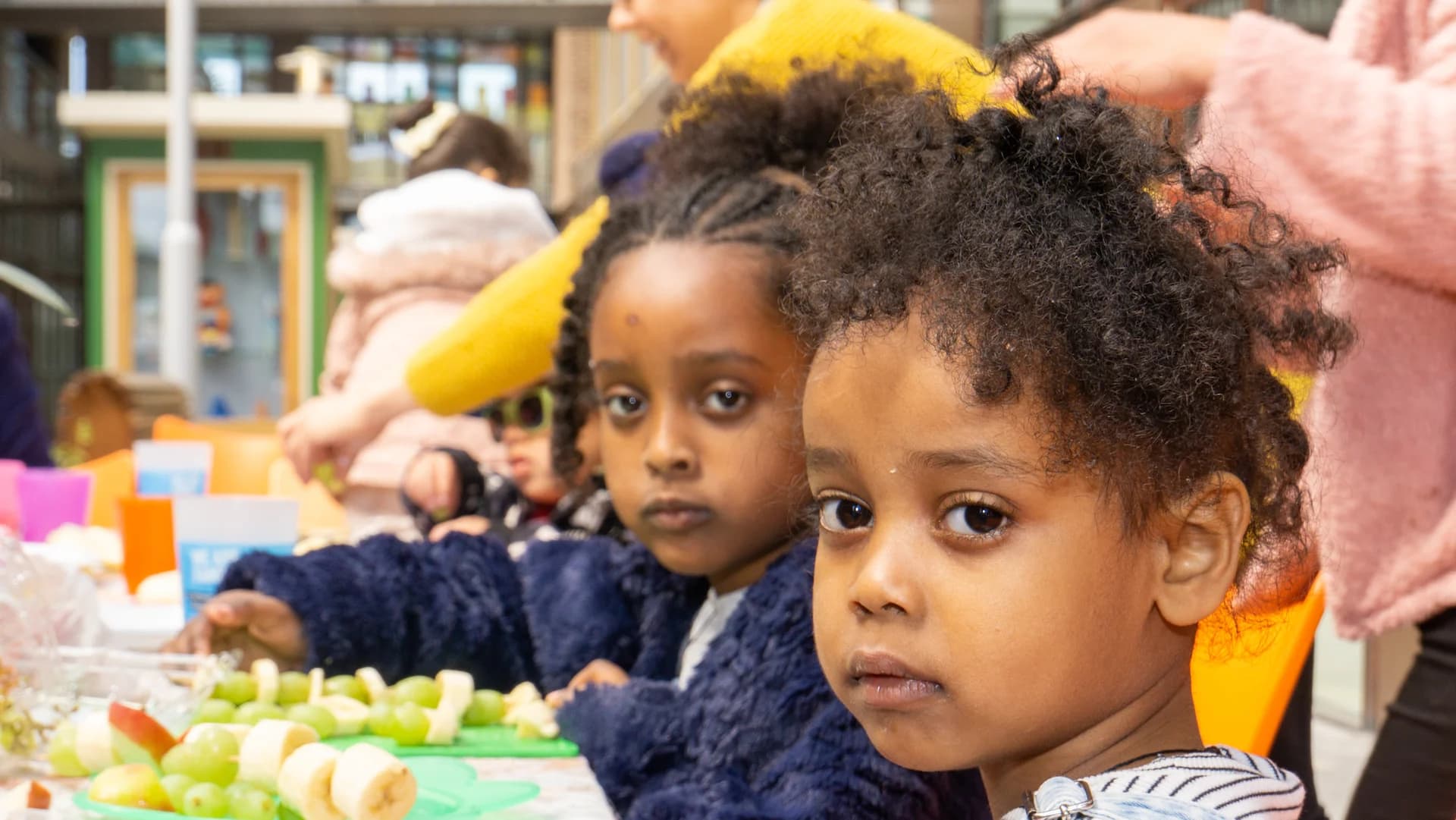 Twee kinderen aan een fruittafel tijdens een buurtactiviteit